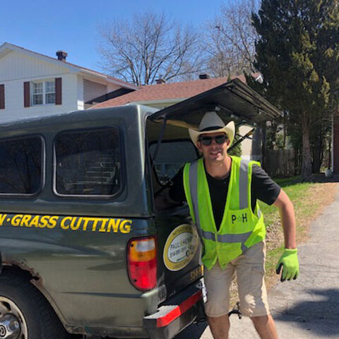 Employee wearing Paul Henry Landscaping safety vest in front of branded truck