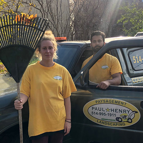 Employees with branded Paul Henry Landscaping uniform pose for a picture with a rake and a visible branded truck